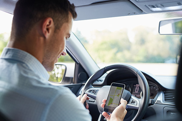 Ablenkung im Straßenverkehr: Autofahrer schaut auf sein Smartphone.