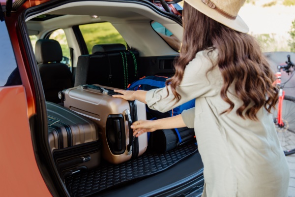 Frau verstaut Reisegepäck möglichst lückenlos im Kofferraum.