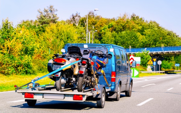 Motorrad transportieren – Van transportiert zwei Motorräder auf einem Anhänger.