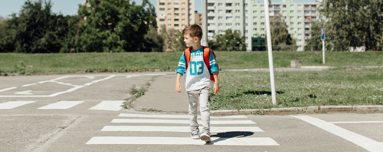 Aller à l’école tout seul : un enfant traverse un passage piéton sur le chemin de l’école.