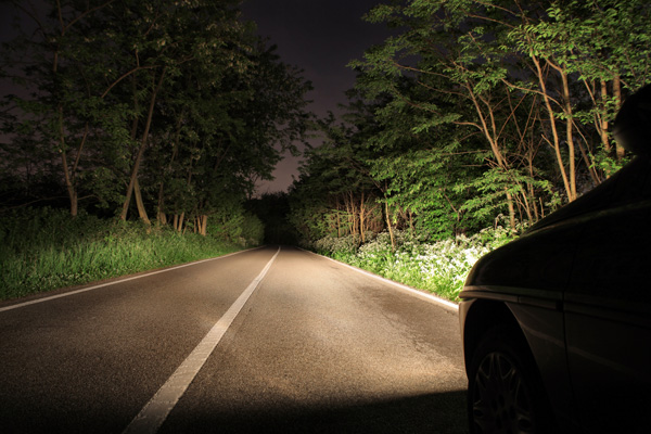 Auto fährt nachts mit Fernlicht.